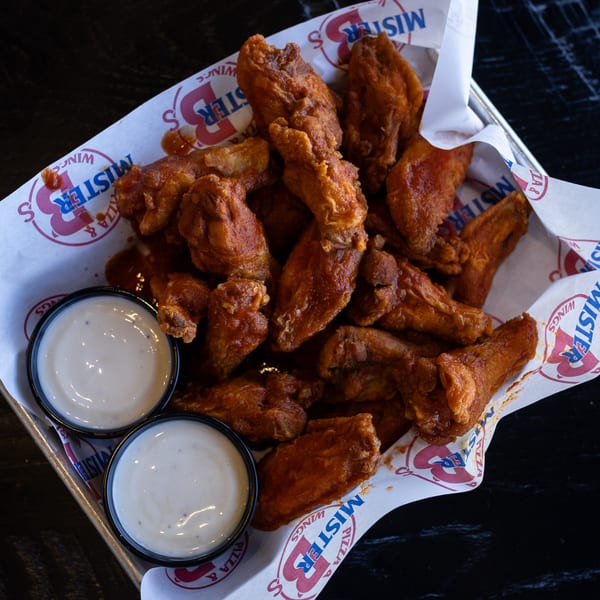 Mister B's Pizza & Wings' basket of saucy chicken wings with two cups of ranch dressing.