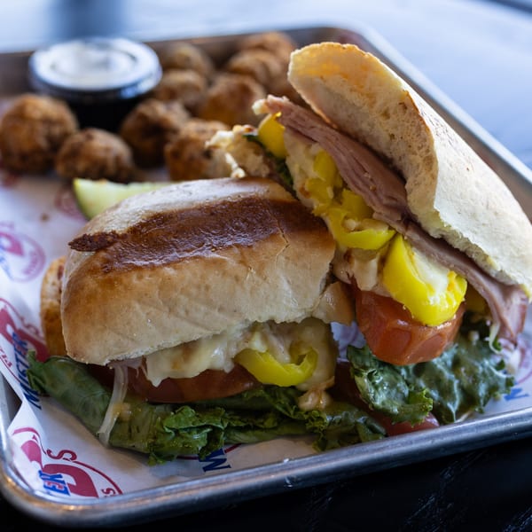 A Mister B's sub sandwich with lettuce, tomato, and peppers, served with fried mushrooms.