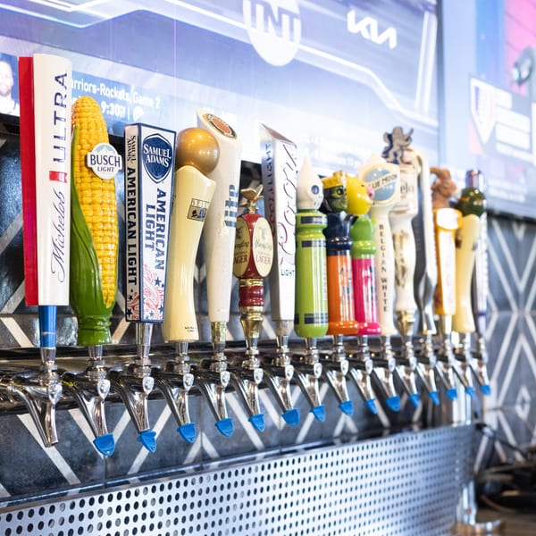 A row of diverse beer taps, including Michelob Ultra, Busch Light, Samuel Adams, and Yuengling.