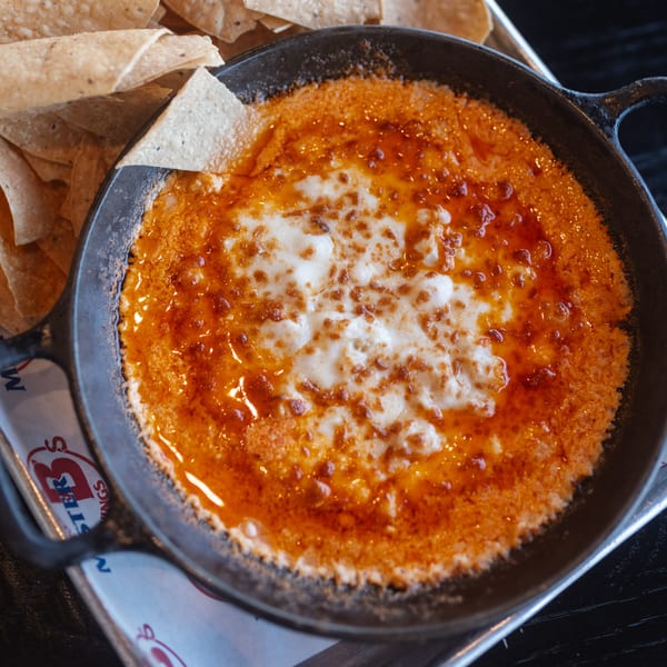 Mister B's Pizza & Wings' cheesy dip with red sauce in a cast iron skillet, served with tortilla chips.