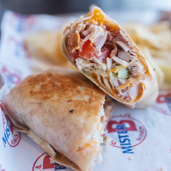 Two Mister B's wraps, one cut in half revealing chicken, cheese, and tomato filling.
