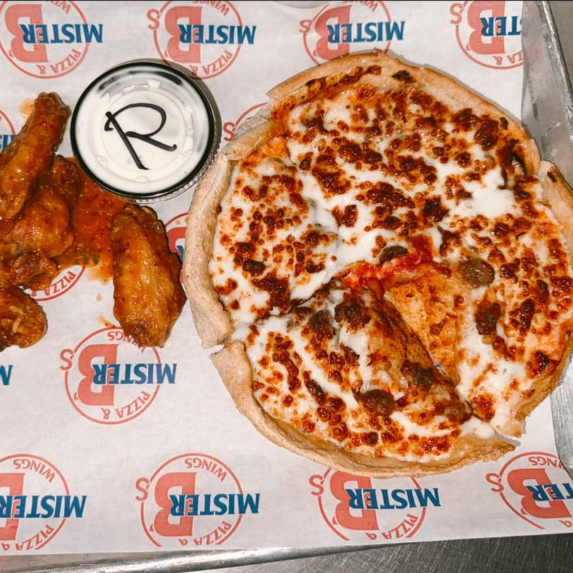 Mister B's Pizza and Wings deep dish pizza, chicken wings, and ranch dressing on branded paper.