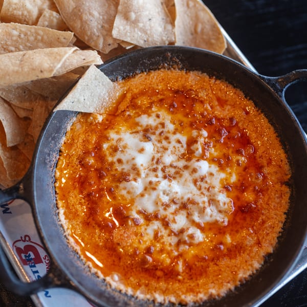 Mister B's Pizza & Wings' cheesy dip with red sauce in a cast iron skillet, served with tortilla chips.